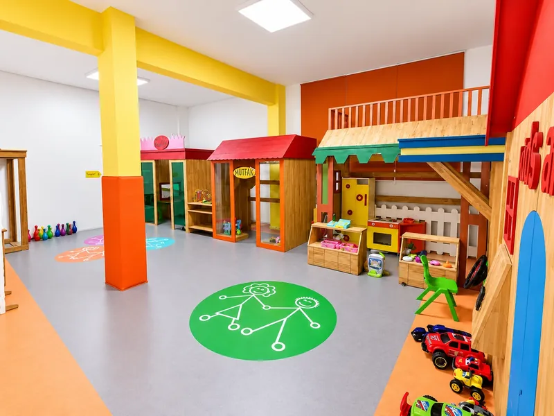 Renkli kolonlar ve ahşap oyun evleriyle düzenlenmiş kapalı oyun alanı