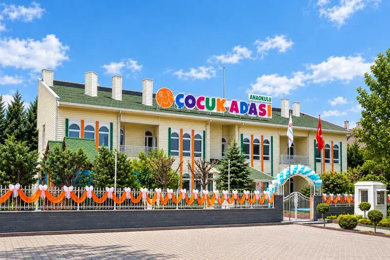 Çocuk Adası tabelalı okul binası ve bahçeli giriş cephesi