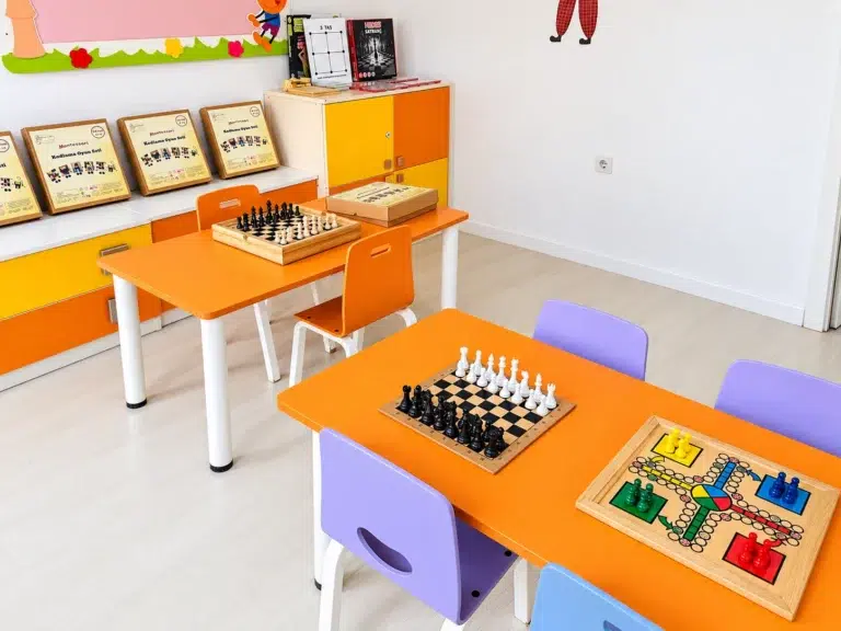 Çocuk masaları üzerinde satranç takımları ve renkli masa oyunları